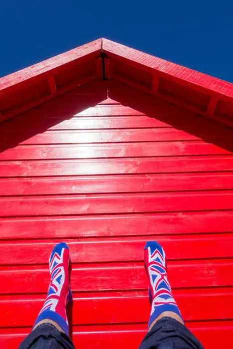 Framed Print : Man wearin Union Jack socks resting against red beach hut on a hot day at the beach. uk Framed Print : Man wearin Union Jack socks resting against red beach hut on a hot day at the beach. uk