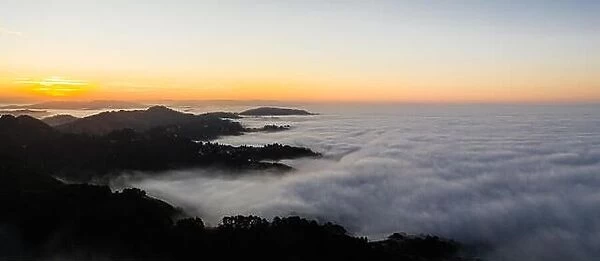 The marine layer, a moist air mass that develops over the ocean in the presence of a temperature inversion, seeps over the Bay Area in California