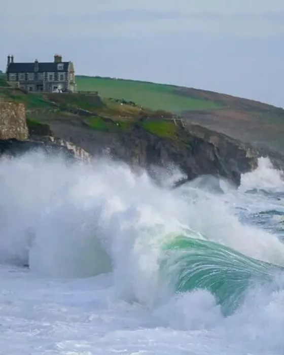 Framed Print : Massive waves pounding into Porthleven beach with Tye Rock Manor perched on the cliff behind Framed Print : Massive waves pounding into Porthleven beach with Tye Rock Manor perched on the cliff behind