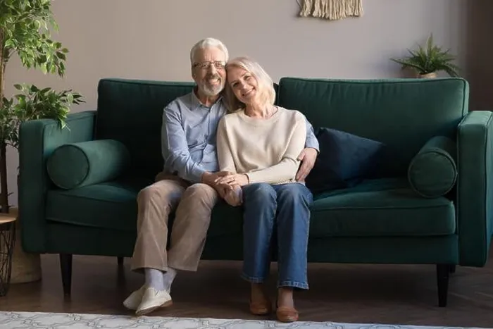 Framed Print : Mature couple embracing sitting on couch posing for camera Framed Print : Mature couple embracing sitting on couch posing for camera