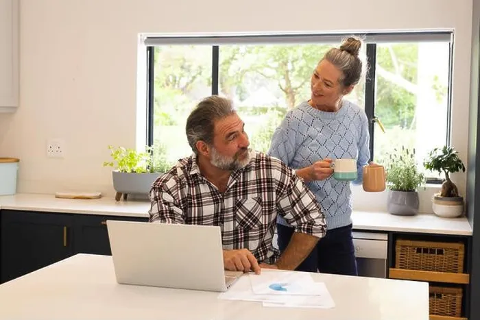 Framed Print : Mature couple enjoying coffee break at home, man using laptop in kitchen Framed Print : Mature couple enjoying coffee break at home, man using laptop in kitchen