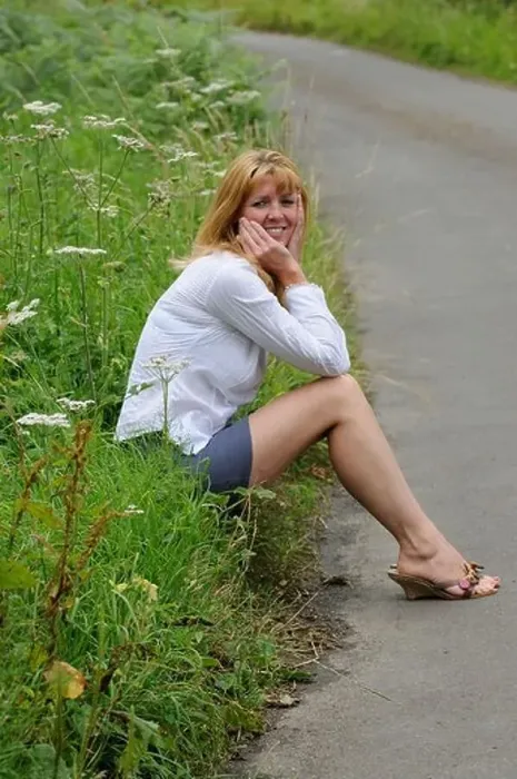 Framed Print : Mature woman wearing a white shirt and short skirt sitting on the roadside Framed Print : Mature woman wearing a white shirt and short skirt sitting on the roadside