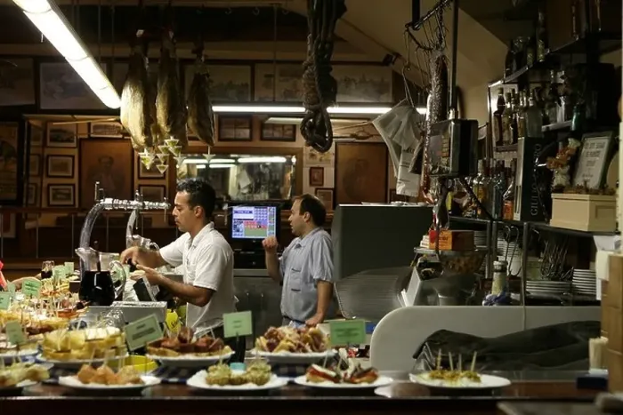 Framed Print : Two men selling pintxos inside a tapas bar in San Sebastian, Basque Country, Northern Spain, Europe