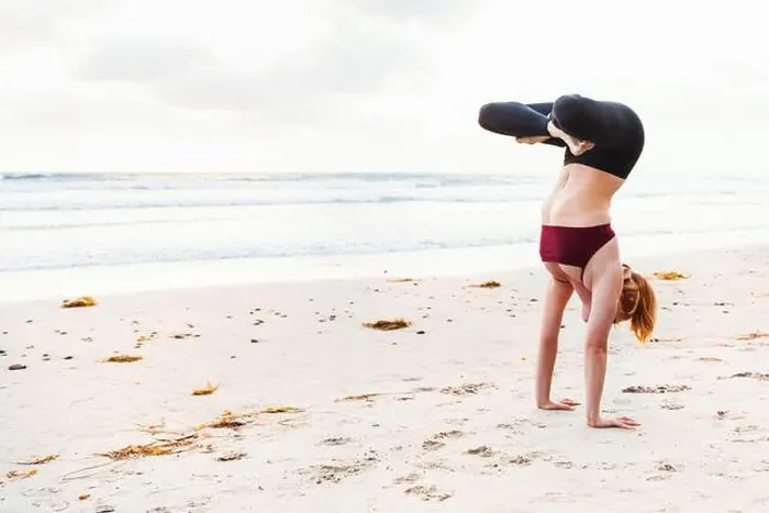 Framed Print : Mid adult woman upside down in yoga position on beach