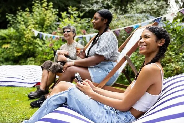 Framed Print : Mixed group of female friends and family gathering to have fun and enjoy a summer BBQ garden party