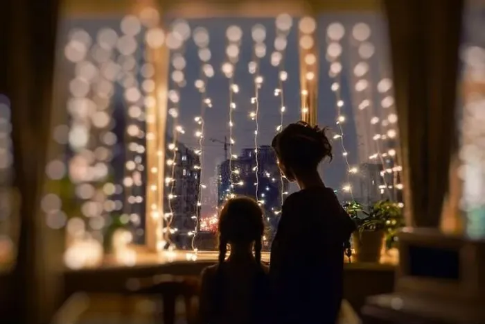 Framed Print : Mother and daughter together standing in the evening, watching the window lights, christmas mood Framed Print : Mother and daughter together standing in the evening, watching the window lights, christmas mood