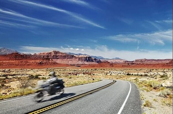 Motorcycle traveler riding in American highway, Glen Canyon, Utah, USA. Main object in motion blur