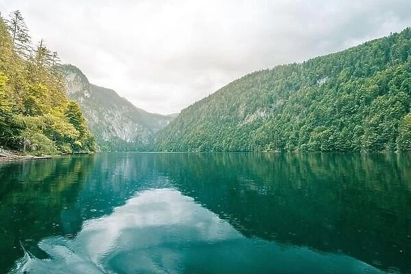 Mountain panorama in a foggy morning with green pine forest and lake reflections. Peaceful spring summer green landscape