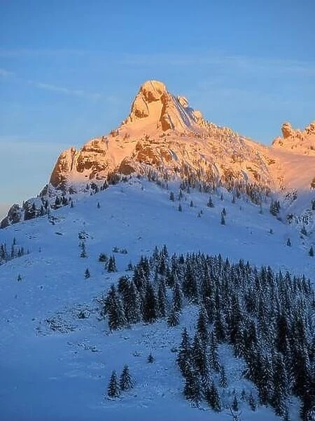 Mountain peak with sharp edges in warm sunrise warm light. Cold winter morning over a snow covered mountain