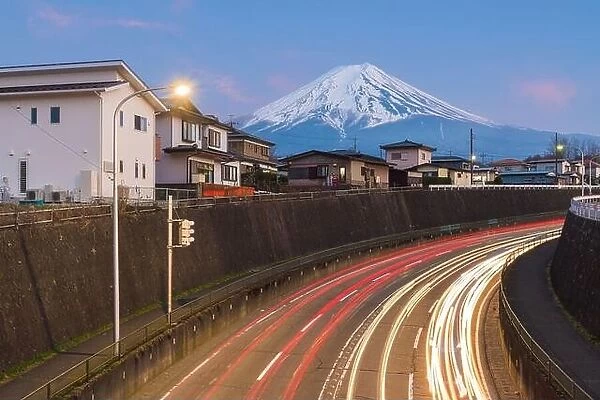 Mt. Fuji, Japan towering over neighborhoods and highways at twilight
