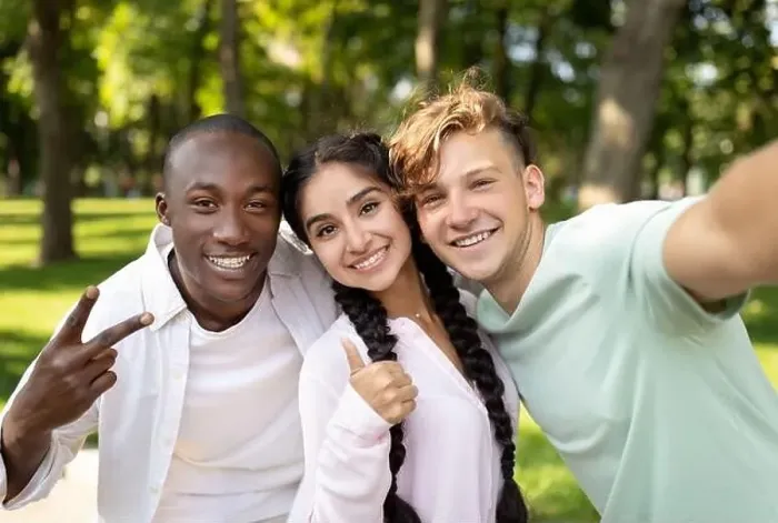 Framed Print : Multiracial students friends making selfie, gesturing v-sign and showing thumb up, posing outdoors in campus
