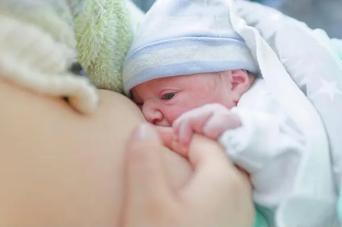Framed Print : Newborn baby breastfeeding while being gently held by mother in soft natural light Framed Print : Newborn baby breastfeeding while being gently held by mother in soft natural light