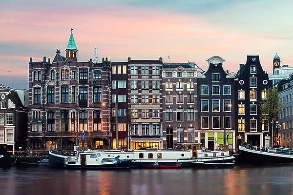 Night Amsterdam city view of Netherlands traditional houses with Amstel river in Amsterdam, Netherlands