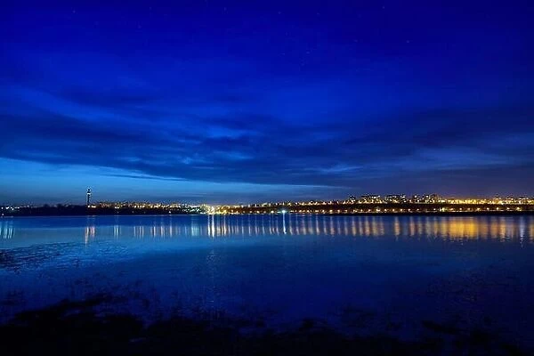 Night view at blue hour of Galati City, Romania with reflections in Danube River and stars on sky