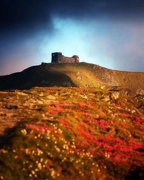 Old Polish observatory White elephant on mt. Pip Ivan top. Spring Carpathians mountains hills covered by pink rhododendron flowers