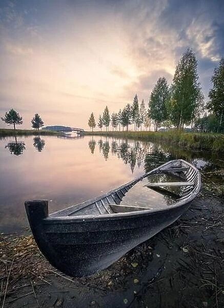 Old rowboat with calm lake and mood sunset at autumn evening in Finland