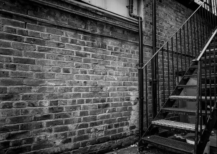 Framed Print : A old run down brick alleyway with a iron stairway in black and white Framed Print : A old run down brick alleyway with a iron stairway in black and white