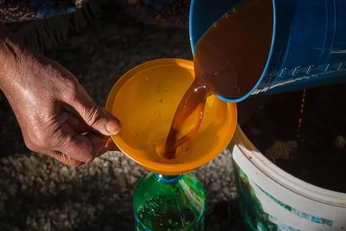 Framed Print : Old woman's hands pouring juice from pan in bottle via funnel Framed Print : Old woman's hands pouring juice from pan in bottle via funnel