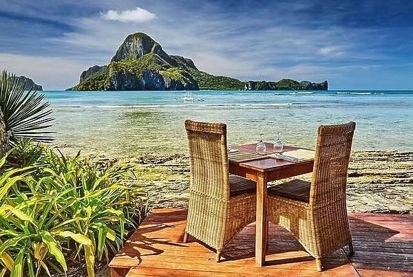 Outdoor terrace of the beach restaurant in front of sea with table and chairs, beautiful view to the Cadlao island, El Nido, Philippines