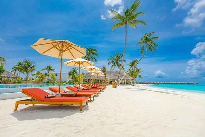 Framed Print : Outdoor tourism landscape. Luxurious beach resort with swimming pool and beach chairs or loungers under umbrellas with palm trees and blue sky. Summer