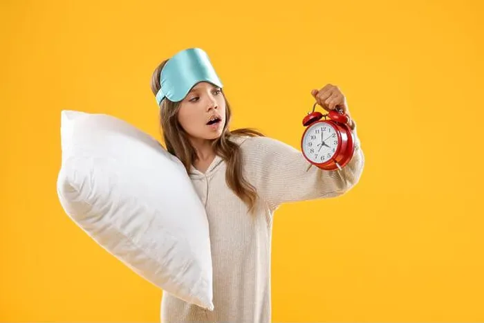 Framed Print : Overslept girl with sleep mask, pillow and alarm clock on orange background