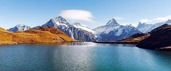 Panorama of Bachalpsee lake in Swiss Alps mountains. Snowy peaks of Wetterhorn, Mittelhorn and Rosenhorn on background