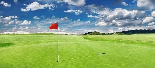 Panorama of golf course with red flag in a hole