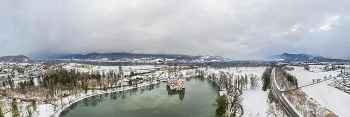 Framed Print : Panoramic aerial view of Schloss Anif moated castle in pond at Salzburg outskirts in heavy snow during winter with view