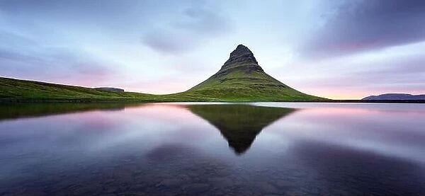 Panoramical landscape with Kirkjufell mountain, clear lake and cloudscape in sunrising sky