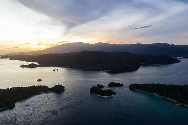 A peaceful sunrise illuminates the remote, tropical islands scattered through Raja Ampat, Indonesia. This area is known for its high biodiversity