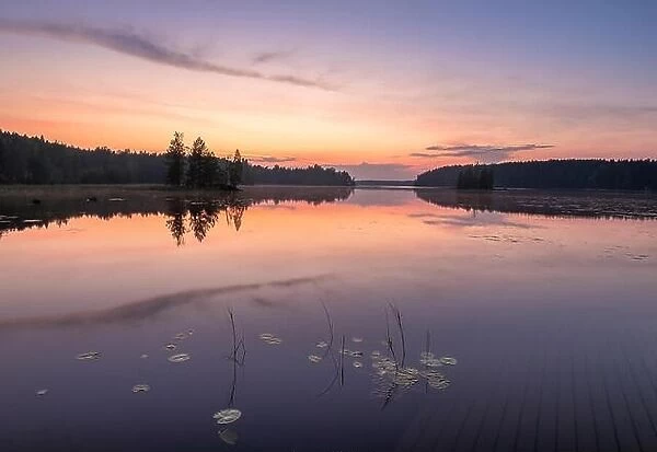 Peaceful view with sunset, lake and standing water at summer night in Finland