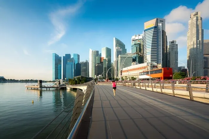 Framed Print : Pedestrians walk along bridge near Marina bay in Singapore with Singapore skyscraper in background Framed Print : Pedestrians walk along bridge near Marina bay in Singapore with Singapore skyscraper in background