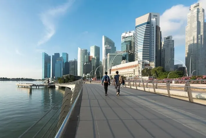 Framed Print : Pedestrians walk along bridge near Marina bay in Singapore with Singapore skyscraper and Merlion park in background Framed Print : Pedestrians walk along bridge near Marina bay in Singapore with Singapore skyscraper and Merlion park in background