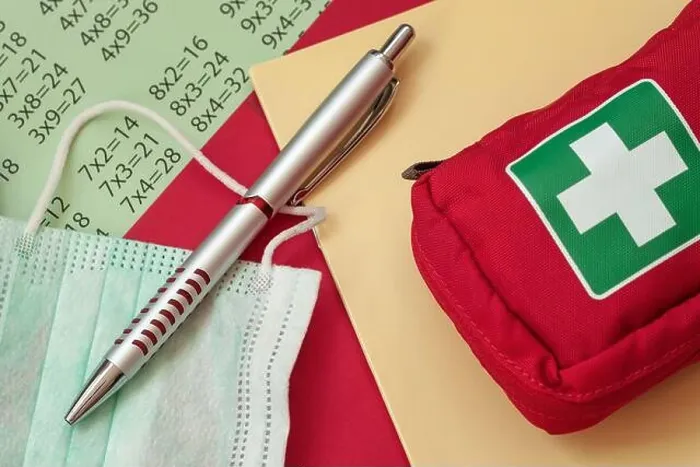 Framed Print : Pen, medical mask and first aid kit on a school notebook
