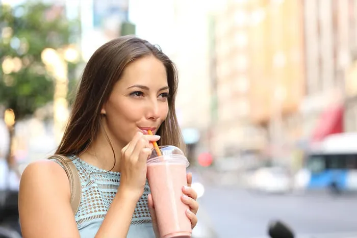 Framed Print : Pensive happy woman sipping a milkshake in the street Framed Print : Pensive happy woman sipping a milkshake in the street