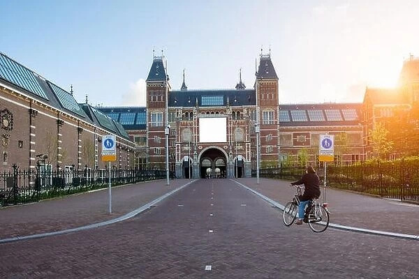 People on bicycles passing by Rijksmuseum (Netherlands National state museum) in Amsterdam, Netherlands. Bicycle - the main means of transportation in