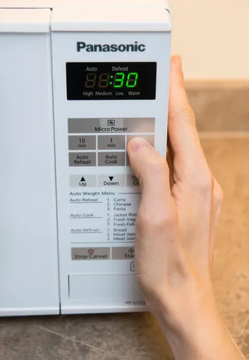 Framed Print : A person setting the timer on a microwave Framed Print : A person setting the timer on a microwave