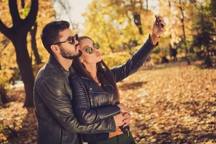 Framed Print : Photo of two people, students girl guy hug make selfie on smartphone send air kiss in fall september park wear jacket