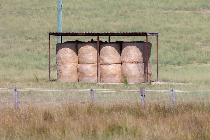 Framed Print : Photograph of a peaceful rural scene featuring bales of hay neatly stacked under a shelter in a grassy field Framed Print : Photograph of a peaceful rural scene featuring bales of hay neatly stacked under a shelter in a grassy field