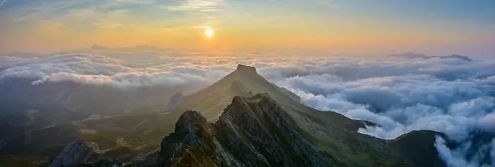 Framed Print : Picturesque aerial view of green mountain range and thick clouds located against morning sky with bright sunrise sun