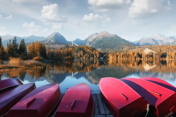 Framed Print : Picturesque autumn landscape with row of red wooden boats and high mountains on background. Strbske pleso lake in High Tatras National Park, Slovakia