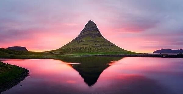 Picturesque panoramical landscape with Kirkjufell mountain, clear lake and cloudscape in sunset sky