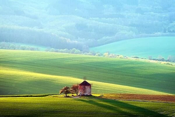 Picturesque rural landscape with old windmill and green sunny spring hills. South Moravia region, Czech Republic