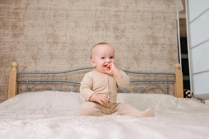 Framed Print : Portrait of cute little baby wearing bodysuit lying on white beedsheets at home Framed Print : Portrait of cute little baby wearing bodysuit lying on white beedsheets at home