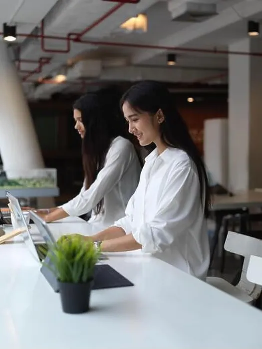 Framed Print : Portrait of female students concentrating on digital tablet while sitting beside each other in co working space Framed Print : Portrait of female students concentrating on digital tablet while sitting beside each other in co working space