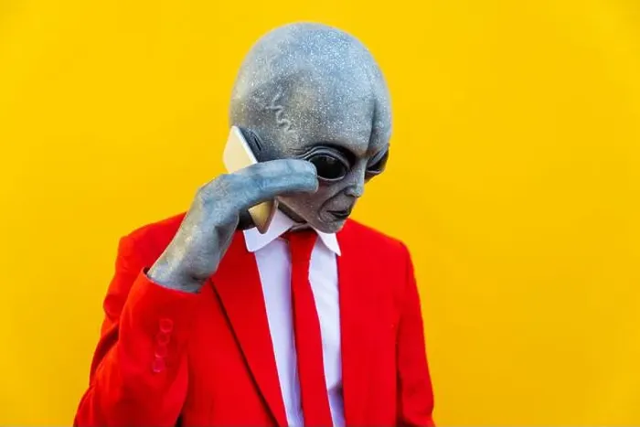 Framed Print : Portrait of man wearing alien costume and bright red suit using smart phone Framed Print : Portrait of man wearing alien costume and bright red suit using smart phone