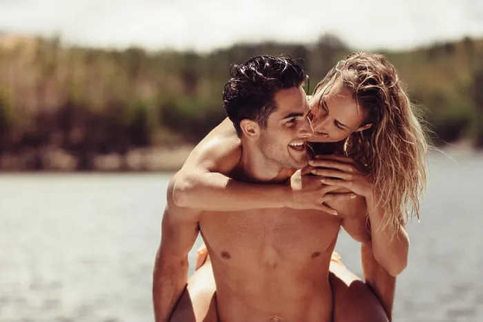 Framed Print : Portrait of romantic young man piggybacking his girlfriend. Young couple having fun at the lakeside