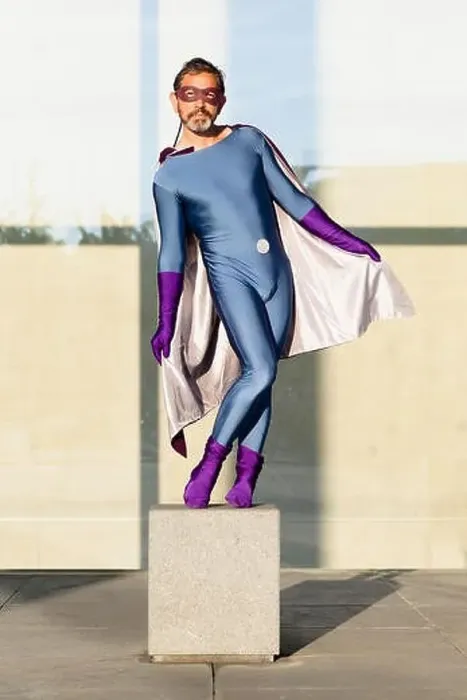 Framed Print : Portrait of superhero holding cape while standing on concrete against glass wall