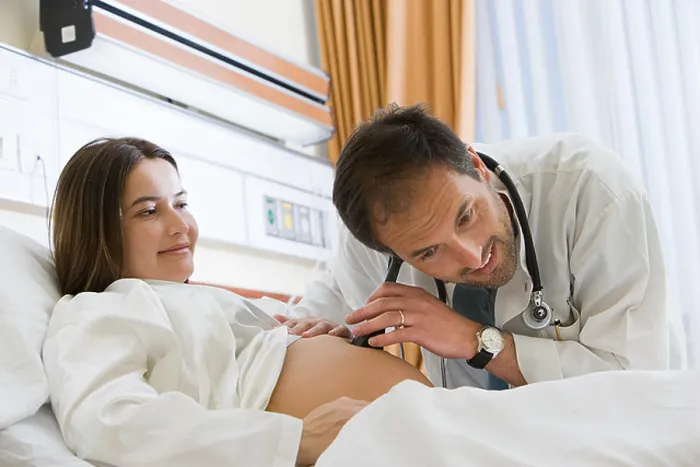 Framed Print : Pregnant woman and doctor listening to stomach Framed Print : Pregnant woman and doctor listening to stomach