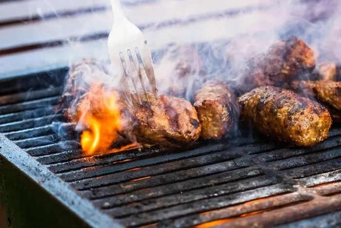 Framed Print : Preparing meat rolls called mici or mititei on barbecue. close up of grill with burning fire with flame and smoke
